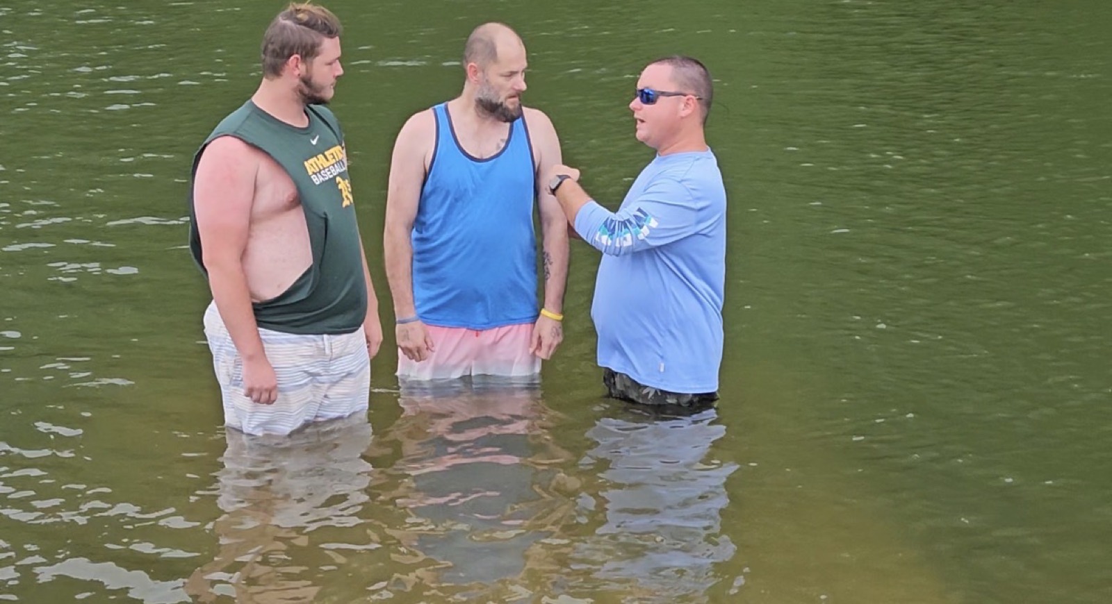 Woodsmen men standing in the water together during a baptism