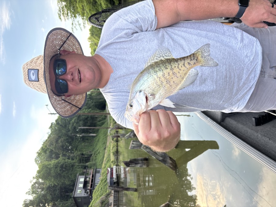 A man on the lake holding a crappie he caught