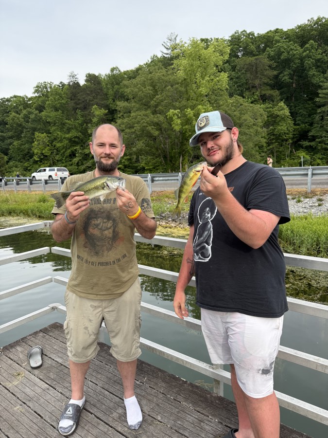Two men on a dock holding their catch