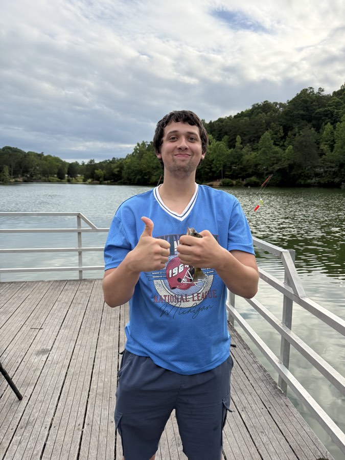 A young man giving a thumbs up with a fish on the dock